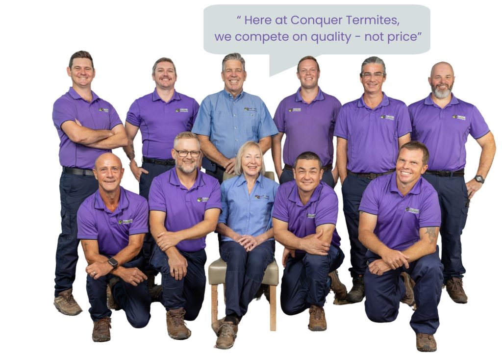 A photo of the Conquer Termites team with a banner saying " Here at Conquer Termites we compete on quality not price'